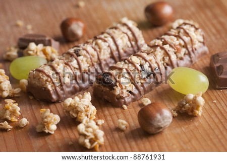 Muesli bars with cereals and grapes on wooden board