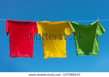 Color shirts on clothesline against blue sky.