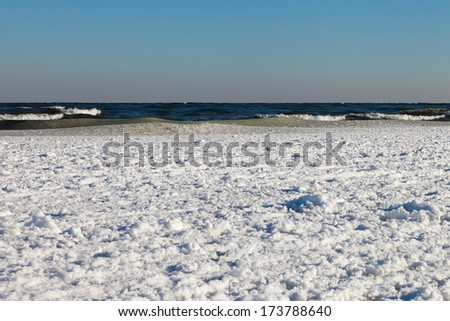 White ice of Baltic sea under clear and blue sky.