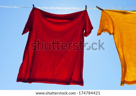 Wet shirts on clothesline against sunlight.
