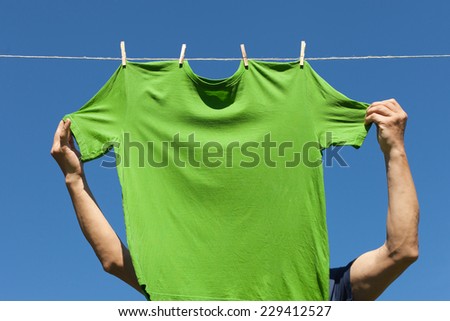 Hand hanging shirt against blue sky.