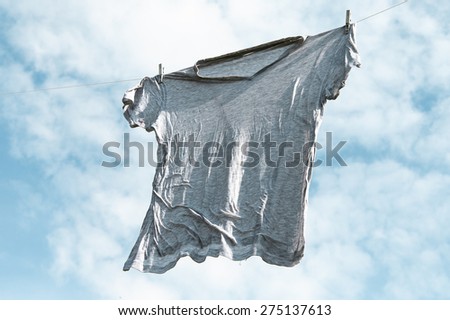 Wet  shirt on clothesline against cloudy sky.