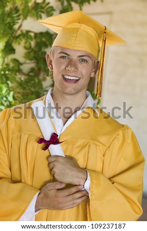 Portrait of a happy young male graduate in yellow gown holding certificate