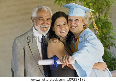 Portrait of a happy senior female graduate embracing family