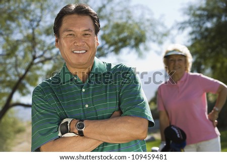 Portrait of a male golfer with woman standing in background