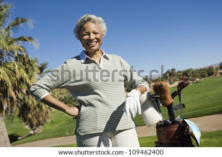 Portrait of happy senior African American woman with golf bag at golf course