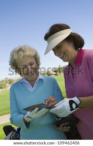 Two female friends writing their golf scores on scorecard