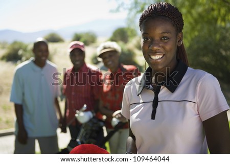 Portrait of happy young African American woman at golf course with people in background