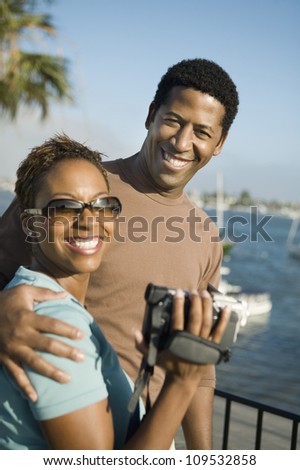 Portrait of a happy African American couple with woman holding handy cam