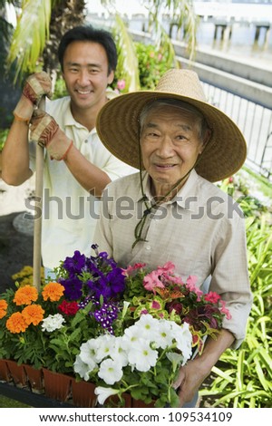 Portrait of a happy senior man with son gardening together