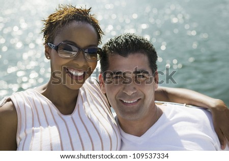 Portrait of happy African American woman standing with around man on the yacht