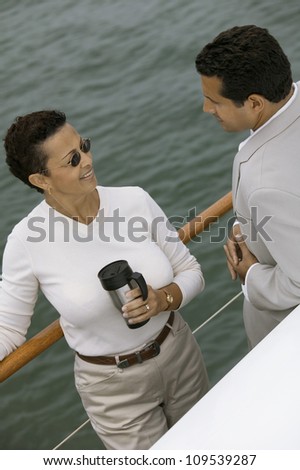 Man and woman having a chat on the yacht while woman having coffee