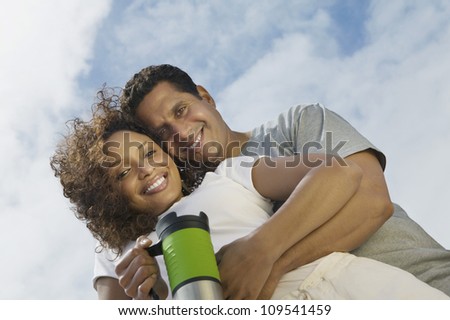 Low angle view of a man embracing woman from behind