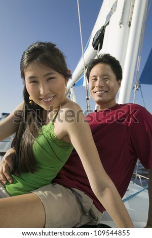 Happy man holding wine glass and bottle while sitting on the yacht