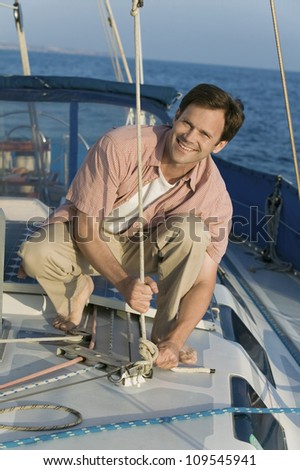Portrait of a happy mature man tying rope on the yacht during vacation