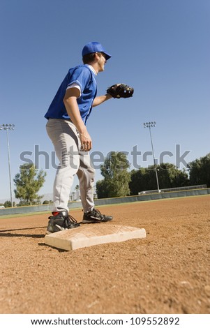 Young baseman covering base at baseball game