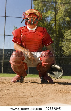 Baseball catcher crouches as gestures a hand sign