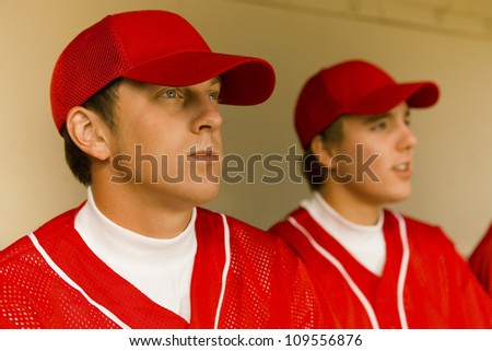 Baseball player sitting with team in dugout
