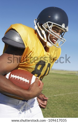 Young African American football player runs while holding ball