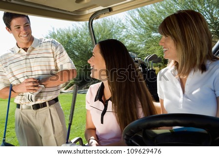 Happy female friends in golf cart looking at man