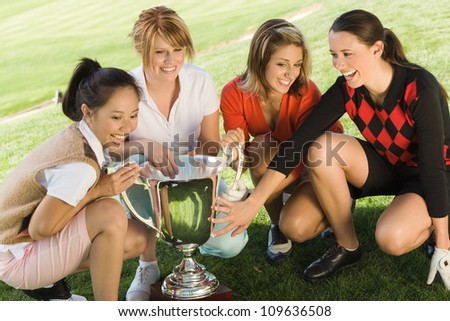 Group of excited female golfers holding winning trophy