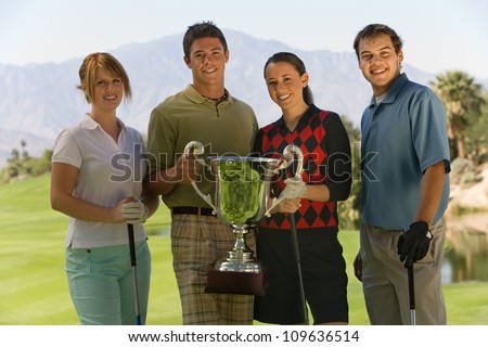 Group portrait of golfers holding their winning trophy on golf course