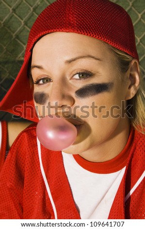 Portrait of a young female softball player eating chewing gum