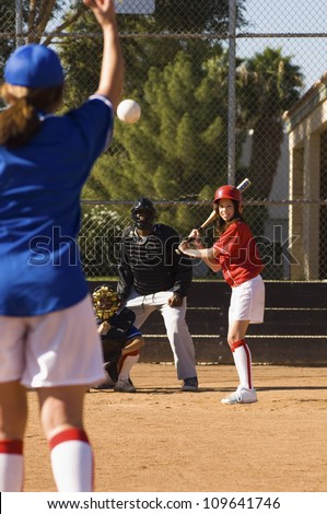 Female softball player ready to hit shot thrown by opposite player