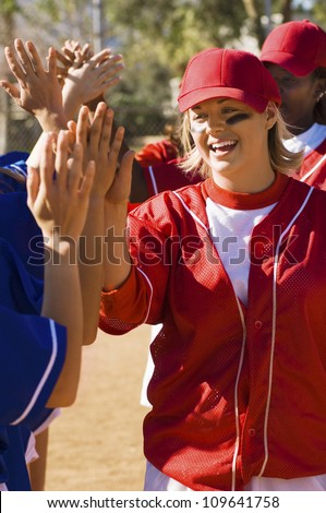 Female softball players giving high five after a winning game