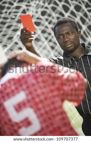 Referee showing red card indicating dismissal for a match to the player