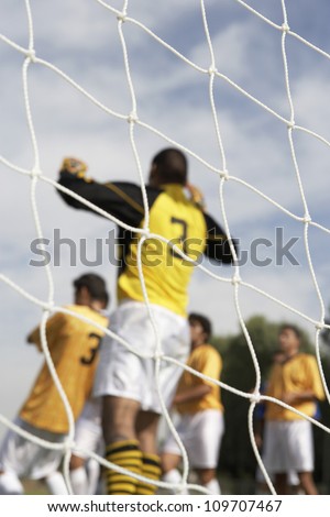 SocCer goalkeeper ready to save the ball with team mates running in the background