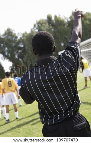 Rear view of an African American soccer referee with players in the background