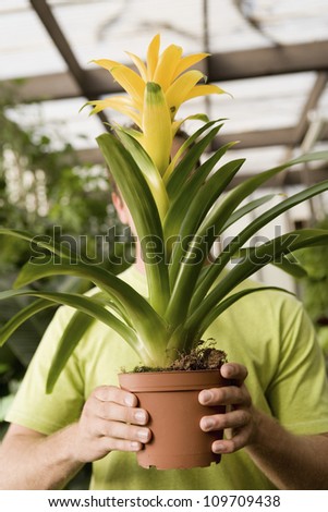 Young man holding potted plant in front of face at botanical garden