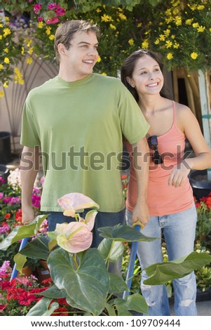 Happy couple gardening with a wheelbarrow at botanical garden