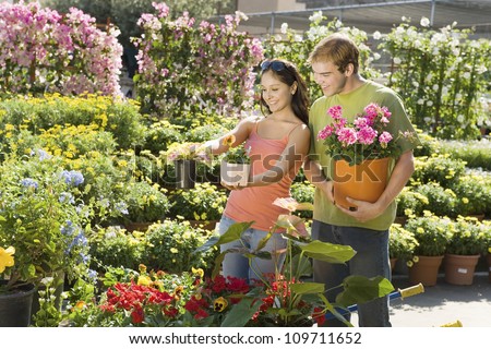 Beautiful young couple selecting plants at botanical garden