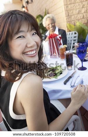 Portrait of a happy asian woman at restaurant with person in background