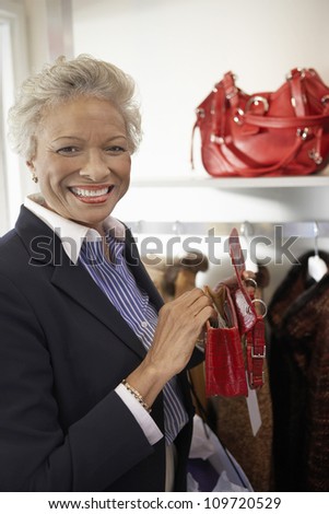 Portrait of a happy African American senior woman holding purse at store