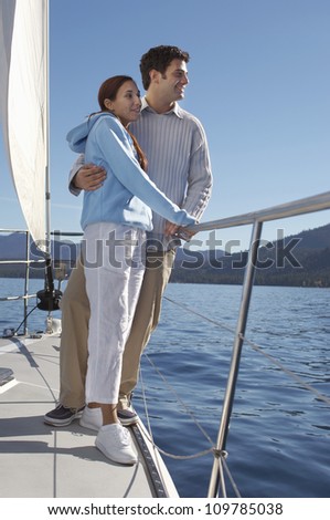 Full length of a happy couple looking away while traveling on sailboat