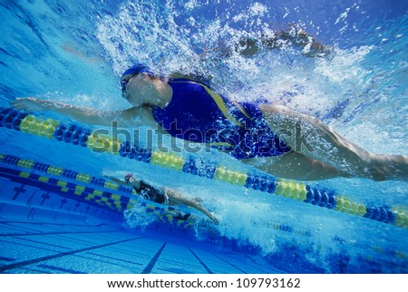Low angle view of female swimmers gushing through water in pool