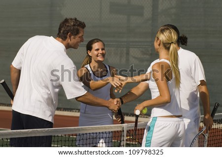 Tennis players shaking hands after match on tennis court