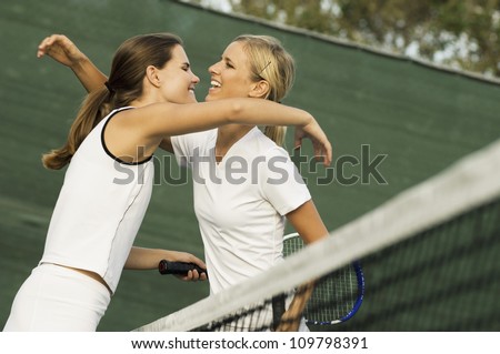 Two happy female tennis player embrace after a winning game