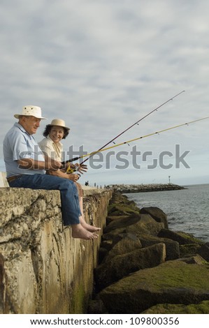 Happy senior couple sitting on rock and fishing
