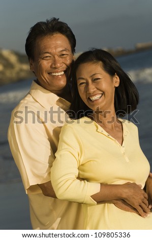 Happy man embracing woman from behind on the beach