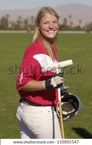 Portrait of happy female player holding polo stick