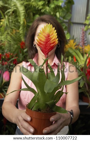 Woman holding potted plant in front of face