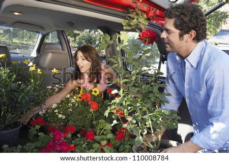 Couple loading plants in car\'s boot
