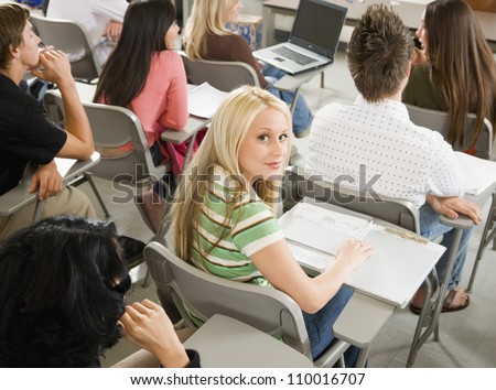 Portrait of young girl studying in classroom with friends in back