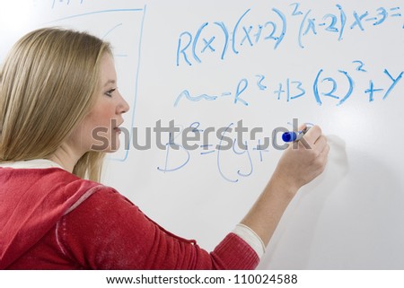 Young student solving mathematics problem on white board