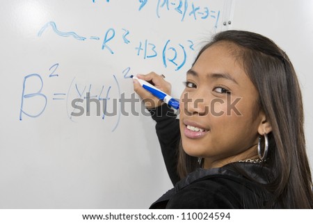 Asian student solving mathematics problem on white board