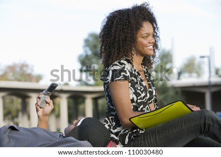 Young African American female student with man using cell phone